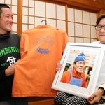 磯谷吉夫さんの写真を手に、阪神・淡路大震災後の歩みを振り返る妻の香代子さん（右）と長男の太朗さん。オレンジのシャツはとんかつ店で着ていたもの＝神戸市灘区稗原町