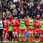 円陣を組み、観客とともに能登半島地震の犠牲者らに黙とうするラグビー神戸の選手＝１４日、神戸市兵庫区御崎町１