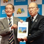 神戸マラソン実行委員会の松本俊裕会長（右）に提言書を手渡す将来構想検討委員会の山口泰雄委員長＝２３日午後、兵庫県民会館