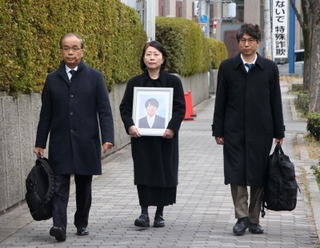 高島晨伍さんの遺影を手に大阪地裁に入る母の淳子さん（中央）ら＝２日午後、大阪市北区
