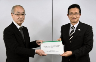 小谷通泰神戸大名誉教授（左）から報告書を受け取る今西正男神戸市副市長＝同市中央区磯辺通２、三宮コンベンションセンター