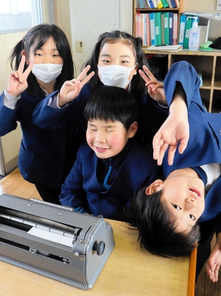 仲良しの友だちと学校生活を楽しむ垣内結都君（中央）。机の上には点字タイプライターが置かれている＝高砂市米田町塩市、米田西小学校