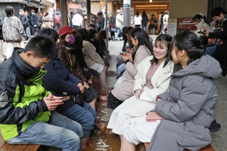２月らしい気温に戻った３連休初日、分厚い上着を着込んだ観光客らで賑わう足湯＝２３日午後、神戸市北区有馬町（撮影・長嶺麻子）