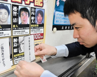 桐島聡容疑者の顔写真に「手配解除」の紙を貼り付ける兵庫県警の担当者＝２７日午後、兵庫県警本部