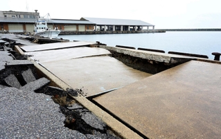アスファルトがひび割れ、波打つ蛸島漁港の岸壁＝２月２５日、石川県珠洲市蛸島町（撮影・中西幸大）