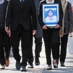 提訴にあたり、岡田幸子さんの遺影を手に神戸地裁に入る遺族（前列２人）や弁護士たち＝神戸市中央区橘通２、神戸地裁