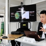 独自開発した培養装置で、人間の脳周辺組織の一部を再現し、抗がん剤の効果を試す実験を行ったことを説明する萩原将也研究チームリーダー（右）＝神戸市中央区港島南町６、理化学研究所生命機能科学研究センタ－