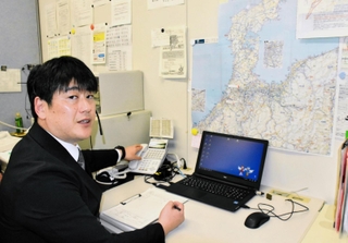 兵庫県警県民広報課で住民からの要望や苦情などに対応している葛西智広さん。壁には能登半島の地図が張り出されている＝神戸市中央区、県警本部