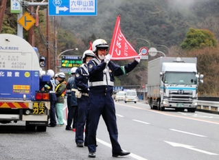 下り坂が続く六甲山トンネルの入り口手前でトラックを止め、エンジンブレーキの活用などを呼びかける警察官たち＝神戸市北区有野町唐櫃