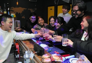 穴場を巡るツアーで訪れたカラオケバーで、スタッフや常連客も交えて乾杯する参加者ら＝神戸市中央区元町通１