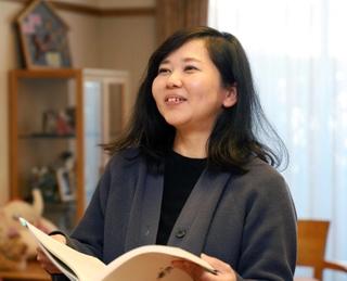 神戸レインボーハウスの冊子を手に、子どものころを思い出す中山舞さん＝神戸市東灘区本庄町１（撮影・長嶺麻子）