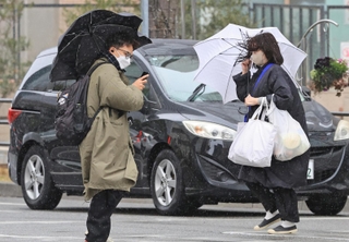 激しい風に雨が加わる中、傘を差して歩く人たち＝２０日午後、神戸市中央区東川崎町１（撮影・小林良多）