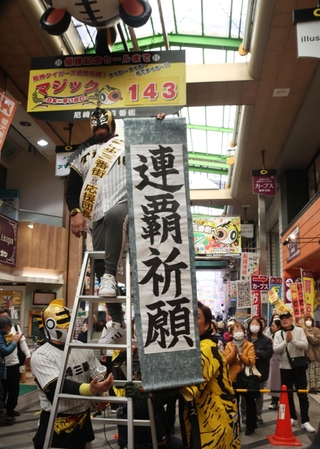 マジックナンバー「１４３」のボードの前で連覇を祈願する商店街関係者＝２７日午前、尼崎市神田中通３