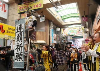 マジックナンバー「１４３」のボードの前で連覇を祈願する商店街関係者＝２７日午前、尼崎市神田中通３