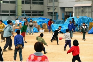 阪神・淡路大震災の避難所となった学校でドッジボール遊びをする子どもたち。校庭には物資が積まれていた＝１９９５年２月、神戸市内