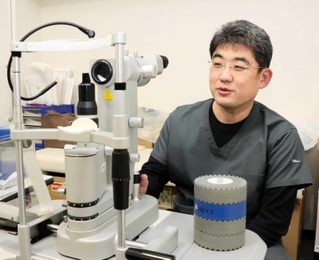 「後発白内障」の治療で用いるＹＡＧレーザーの照射器を扱う渡部暁也医師＝尼崎市潮江１、渡部眼科