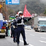 下り坂が続く六甲山トンネルの入り口手前でトラックを止め、エンジンブレーキの活用などを呼びかける警察官たち＝神戸市北区有野町唐櫃