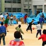 阪神・淡路大震災の避難所となった学校でドッジボール遊びをする子どもたち。校庭には物資が積まれていた＝１９９５年２月、神戸市内
