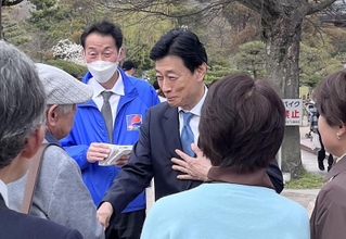 公園の来園者と握手する西村康稔氏＝６日午後、明石市の兵庫県立明石公園
