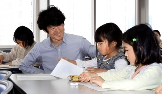 震災学校で子どもたちに優しく語りかける長谷川元気さん（左から２人目）＝６日午後、神戸市中央区、神戸新聞社（撮影・笠原次郎）