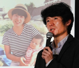 震災で亡くなった母と弟の写真を背に当時について子どもたちに語る長谷川元気さん＝６日午後、神戸市中央区東川崎町１、神戸新聞社（撮影・笠原次郎）
