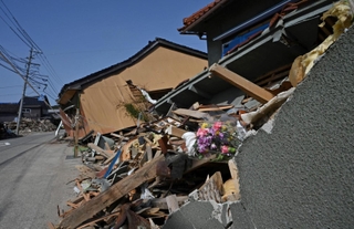 倒壊した民家が残ったままの能登半島地震の被災地。犠牲者が集中した地区では、花が供えられている家屋もあった＝３月３０日、石川県珠洲市宝立町（撮影・斎藤雅志）