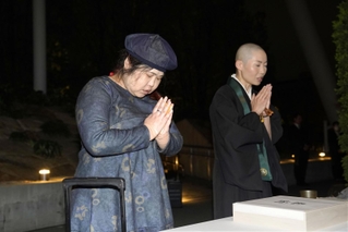 尼崎ＪＲ脱線事故の追悼行事で、写経を奉納し手を合わせる増田和代さん（左）と僧侶の露の団姫さん＝２４日夜、尼崎市久々知３（代表撮影）