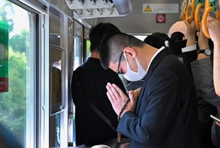 尼崎ＪＲ脱線事故の発生現場付近を走行中の快速電車内で、犠牲者の冥福を祈る乗客ら＝２５日午前９時１５分、尼崎市内（撮影・斎藤雅志）