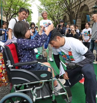 開幕２０日前イベントで金メダルレプリカを順番にリレーする参加者。右はやり投げ種目で出場する白砂匠庸さん＝２７日午後、神戸市中央区明石町（撮影・小林良多）