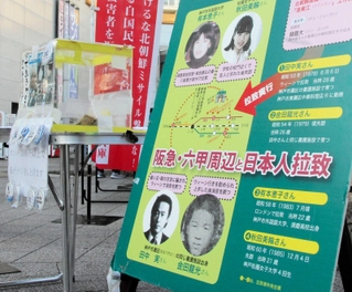 田中実さんら兵庫県内の拉致被害者や特定失踪者の写真を掲げて行われた署名活動＝２０２３年１２月、ＪＲ六甲道駅前