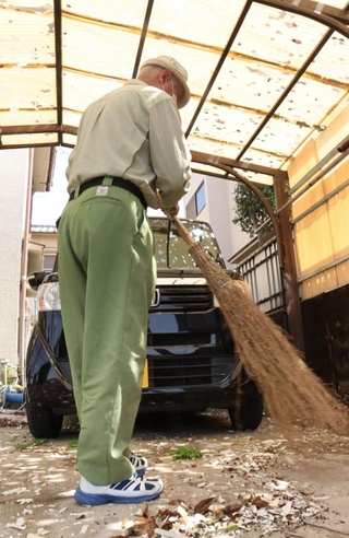 ひょうが降り割れたカーポートの破片を掃除する地域住民＝加古川市平岡町二俣（撮影・斎藤　誉）