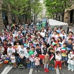 開幕２０日前イベントで万国旗を手に記念写真を撮る参加者＝２７日午後、神戸市中央区明石町（撮影・小林良多）