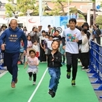 開幕２０日前イベントで開かれた走り方教室で北京五輪銀メダリストの朝原宣治さんと走る参加者＝２７日午後、神戸市中央区明石町（撮影・小林良多）