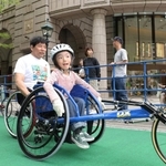 開幕２０日前イベントで競技用車いすを体験する子どもら。中央はアテネパラ銅メダリストの永尾嘉章さん＝２７日午後、神戸市中央区明石町（撮影・小林良多）