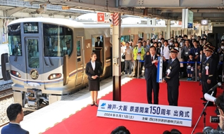 記念列車のそばで、駅名標を手に記念撮影する神戸市の久元喜造市長ら＝１１日午前、同市中央区相生町３、ＪＲ神戸駅（撮影・小林良多）