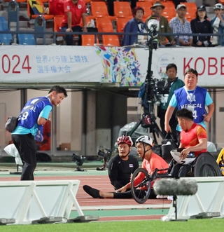 競技用車いす（レーサー）が接触して複数人の選手が転倒し、選手の状態を確認するメディカルスタッフら＝１８日午後、ユニバー記念競技場（撮影・小林良多） 