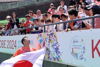 男子円盤投げ（脳性まひＦ３７）決勝で銅メダルに輝き、応援に駆けつけた関係者と喜ぶ新保大和（左下）＝神戸市須磨区、ユニバー記念競技場（撮影・小林良多）