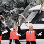 船上からハモを勢いよく海へ投げ入れる「鱧供養祭」の参列者ら＝15日午前、南あわじ市沼島