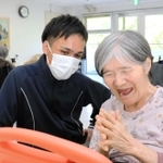 自ら開発したアプリを使って、利用者の女性と一緒に動画を見て楽しむ溝田ラビさん（左）＝神戸市北区山田町、特別養護老人ホーム「六甲の館」