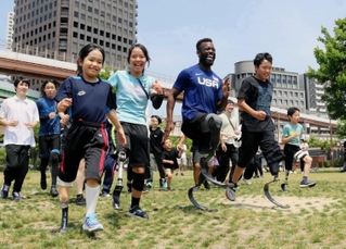 ブレーク・リーパー選手とともにスポーツ用義足でランニングする参加者ら＝みなとのもり公園