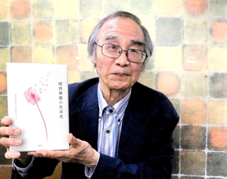 聞き取り開始から１７年。華僑約５０人の生活史をまとめた本を手にする呉宏明さん＝神戸市中央区、神戸華僑歴史博物館
