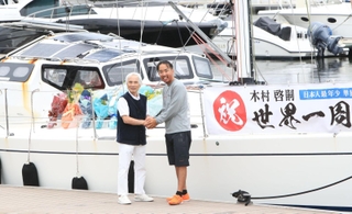 ミランダ号の前で堀江謙一さん（左）と握手する木村啓嗣さん＝９日午前、西宮市西宮浜４、新西宮ヨットハーバー（撮影・吉田敦史）