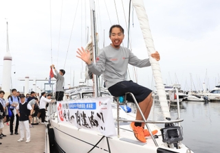 ミランダ号のへさきで手を振る木村啓嗣さん＝９日午前、西宮市西宮浜４、新西宮ヨットハーバー（撮影・吉田敦史）