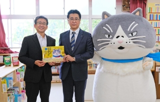 中島竜也社長（中央）から絵本を受け取る横谷義秀校長＝神戸市垂水区千鳥が丘３