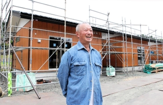 集落への思いを語る左部淳一さん。後ろは、被災地で唯一建設が進む「ふるさと回帰型応急仮設住宅」＝石川県穴水町下唐川