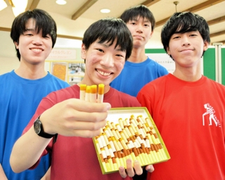 オオキンケイギクの花びらから作ったクレヨンを手にする浅井勇輝さんら＝三田市学園１、三田祥雲館高校