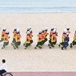 初夏の砂浜で、防火衣を着て走る消防学校の学生たち＝神戸市須磨区若宮町１