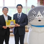 中島竜也社長（中央）から絵本を受け取る横谷義秀校長＝神戸市垂水区千鳥が丘３