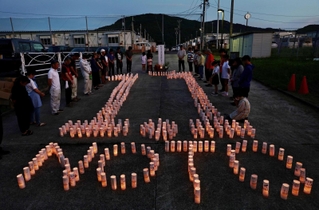 神戸から分灯した火でかたどった「１．１」の文字を囲み、黙とうする人たち＝１日夜、石川県輪島市町野町（撮影・長嶺麻子）