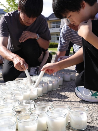 「１・１７希望の灯り」から分灯した火を、「１．１」と形作ったローソクにともしていく地元の子どもら＝１日午後４時４分、石川県輪島市町野町、町野小学校（撮影・長嶺麻子）